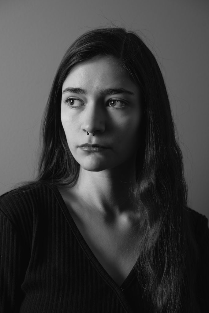 Black and white image of a woman with a somber look wearing a black shirt