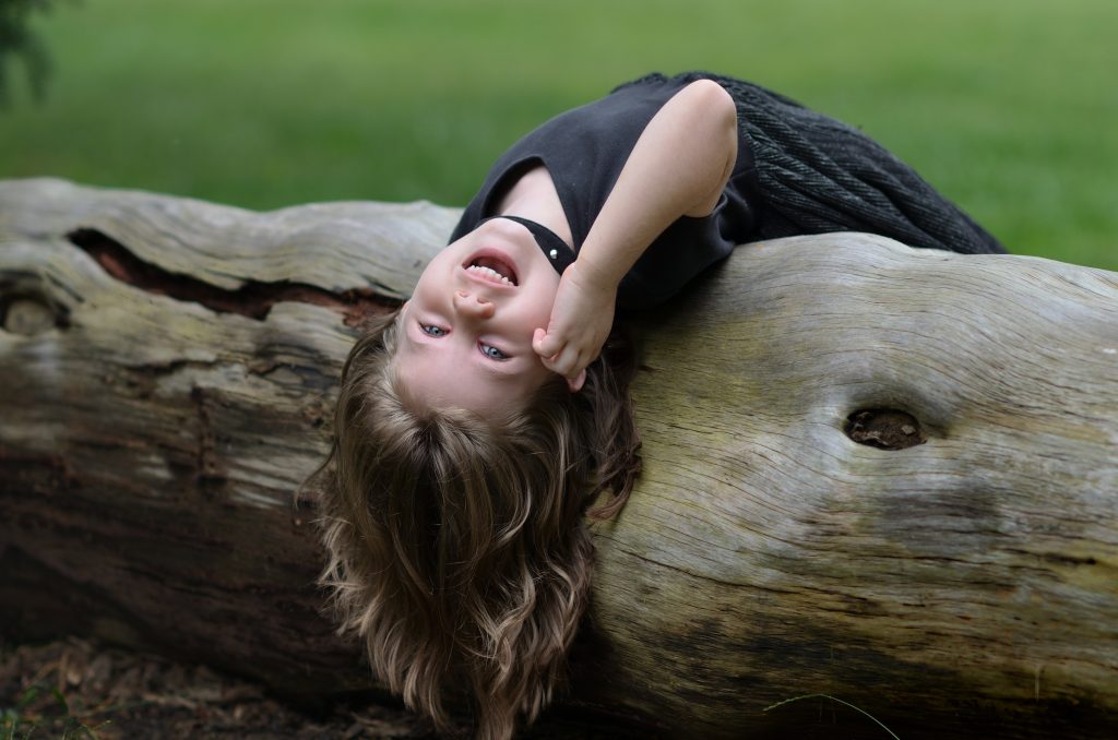Portrait of a girl wearing a flowy black dress laying on a fallen tree with trees in the background, Lyssa Benavidez Photography Elkhorn, NE Lyssab.com Family photography. 