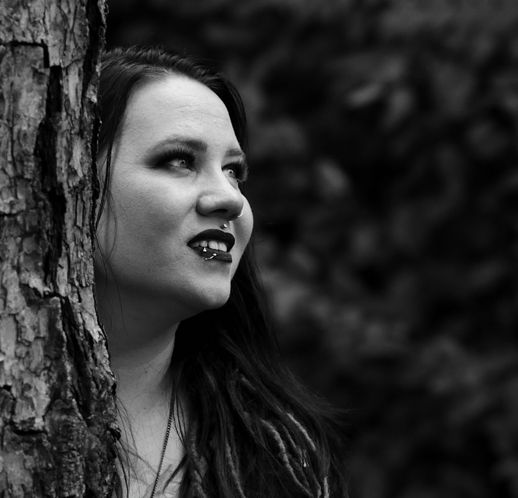 Black and white close up portrait of a woman wearing a black shirt looking off into the distance with bushes in the background. Lyssa Benavidez Photography Elkhorn, NE Lyssab.com Family photography. 