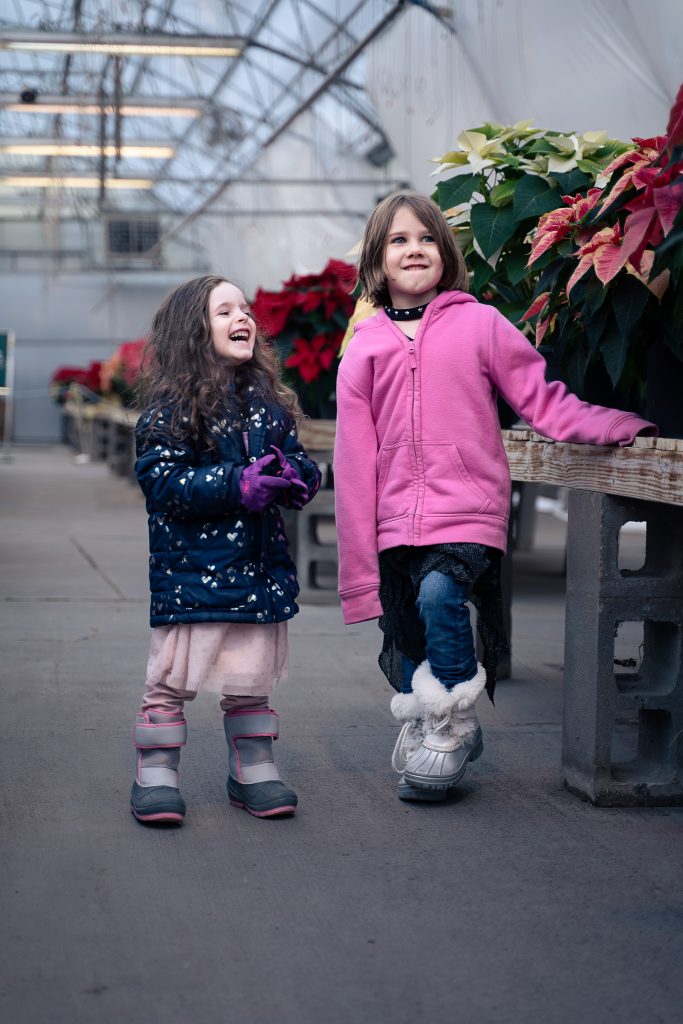 Portrait of two girls laughing together with plants in the background. Lyssa Benavidez Photography Elkhorn, NE Lyssab.com Lifestyle family photography