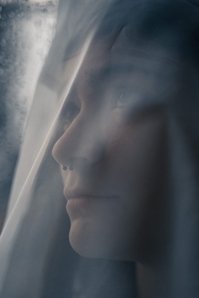 Fine art portrait of a woman looking up under a veil standing in front of a window. Lyssa Benavidez Photography Elkhorn, NE Lyssab.com Fine Art Photography