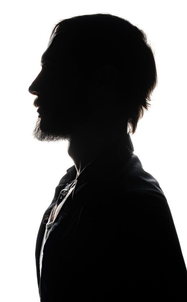 Dramatic studio portrait silhouette of the side profile of a man against a bright white background. Lyssa Benavidez Photography Elkhorn, NE studio photography. 