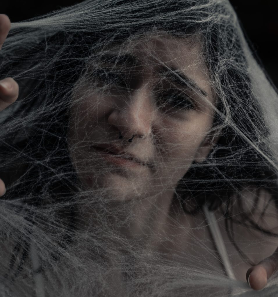 Surrealist portrait of a woman somberly looking at the camera under spiderwebs. Lyssa Benavidez Photography Elkhorn, NE Lyssab.com Fine Art Photography surrealist photography