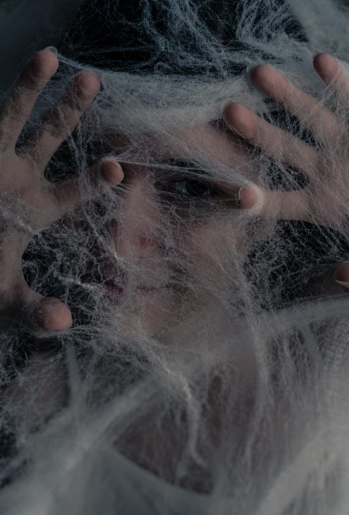 Surrealist portrait of a woman looking at the camera under spiderwebs with just one eyeball peeking out of them. Lyssa Benavidez Photography Elkhorn, NE Lyssab.com Fine Art Photography