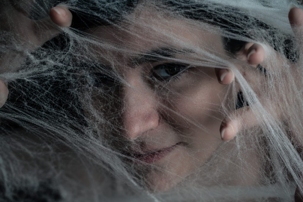 Surrealist portrait of a woman looking at the camera under spiderwebs with just one eyeball peeking out of them. Lyssa Benavidez Photography Elkhorn, NE Lyssab.com Fine Art Photography