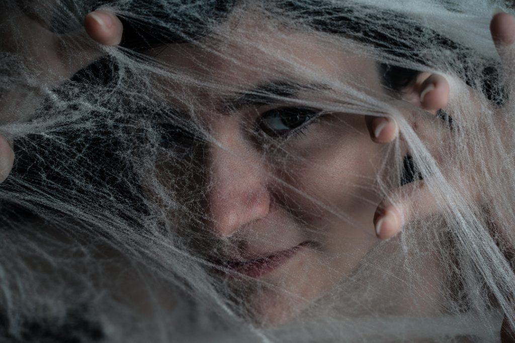 Surrealist portrait of a woman looking at the camera under spiderwebs with just one eyeball peeking out of them. Lyssa Benavidez Photography Elkhorn, NE Lyssab.com Fine Art Photography
