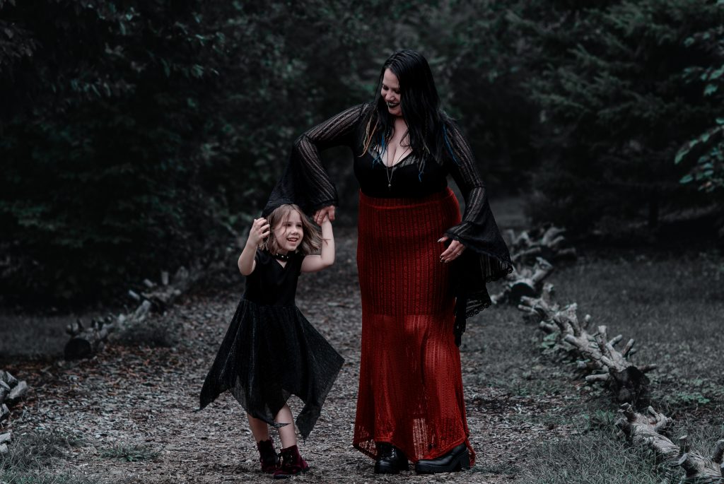 A woman and a girl dancing in a forest on a lined path wearing black and red clothes